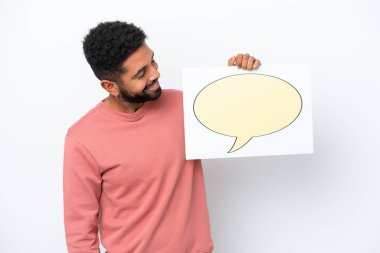 Young Brazilian man isolated on white background holding a placard with speech bubble icon
