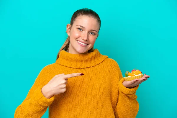 Young Caucasian Woman Holding Tartlet Isolated Blue Background Pointing — Stock Fotó