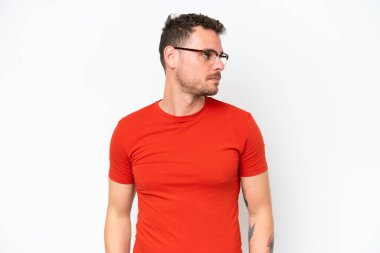 Beyaz arka planda soyutlanmış beyaz tenli yakışıklı bir adam yan tarafa bakıyor.