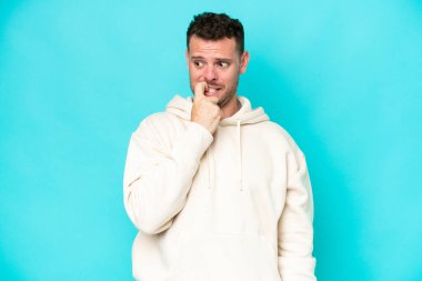 Kafkasyalı yakışıklı adam mavi arka planda izole edilmiş gergin ve korkmuş.