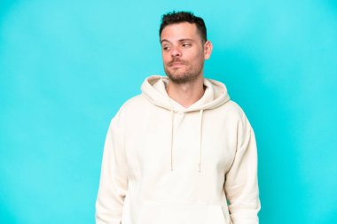 Mavi arka planda mahsur kalmış beyaz, yakışıklı genç bir adam.