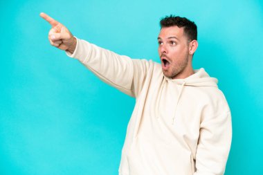 Kafkasyalı yakışıklı genç adam mavi arka planda izole edilmiş.