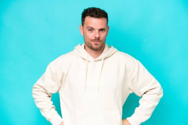 Kafkasyalı yakışıklı genç adam mavi arka planda izole edilmiş kızgın.