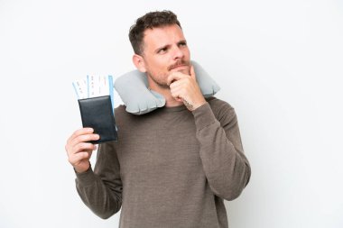 Young caucasian man holding a passport isolated on white background having doubts