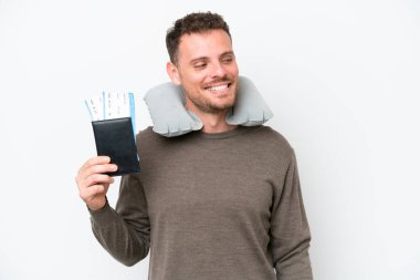 Young caucasian man holding a passport isolated on white background looking to the side and smiling