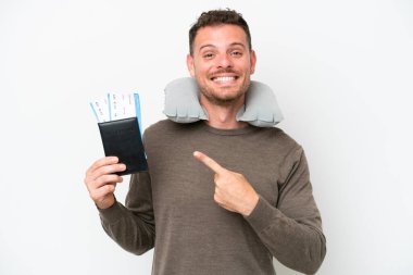 Young caucasian man holding a passport isolated on white background pointing to the side to present a product