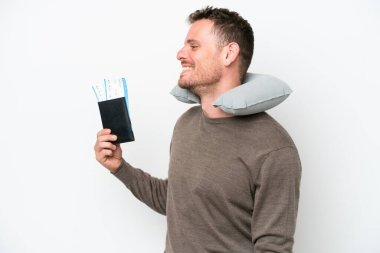 Young caucasian man holding a passport isolated on white background laughing in lateral position