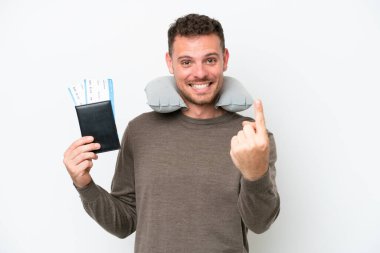 Young caucasian man holding a passport isolated on white background doing coming gesture