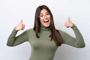 Beyaz arka planda izole edilmiş genç Brezilyalı bir kadın baş parmak hareketi yapıyor.