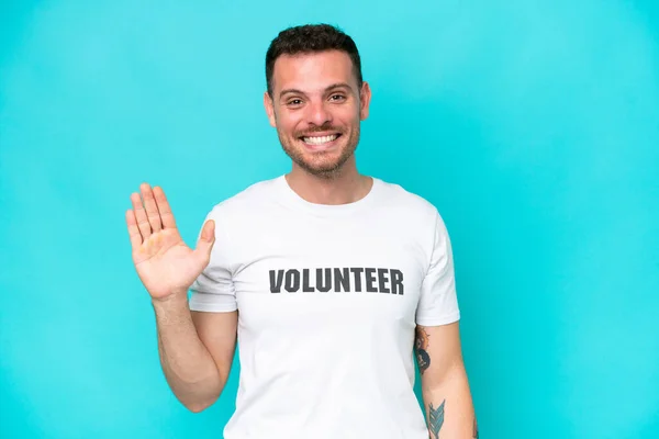Young Volunteer Caucasian Man Isolated Blue Background Saluting Hand Happy — Photo