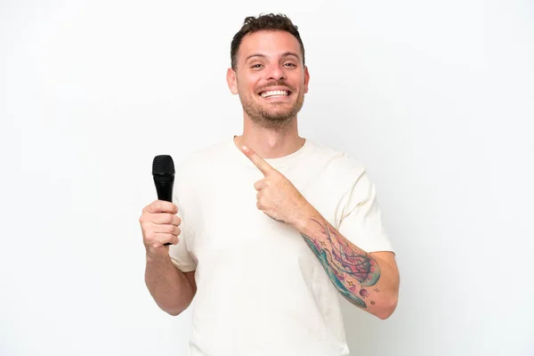 Young Caucasian Singer Man Picking Microphone Isolated White Background Pointing — Stockfoto