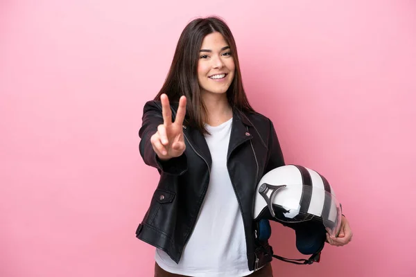 若いですブラジル人女性とともにオートバイヘルメット隔離ピンクの背景笑顔と勝利のサインを示す — ストック写真