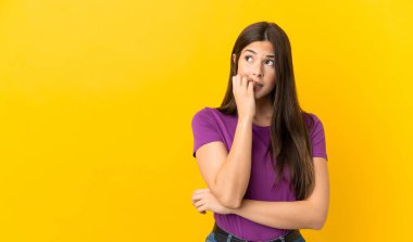 Teenager Brazilian girl over isolated yellow background is a little bit nervous