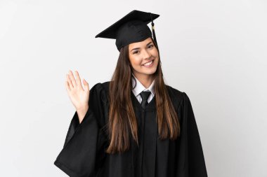 Teenager Brazilian university graduate over isolated white background saluting with hand with happy expression