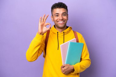 Young student Brazilian man isolated on purple background showing ok sign with fingers