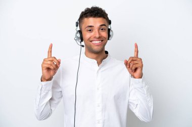 Tele pazarlamacı Brezilyalı adam beyaz arka planda izole edilmiş kulaklıkla çalışıyor. Harika bir fikre işaret ediyor.