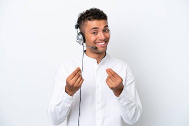 Tele pazarlamacı Brezilyalı adam beyaz arka planda izole edilmiş bir kulaklıkla para hareketi yaparak çalışıyor.