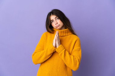 Mor arka planda izole edilmiş genç beyaz kadın avuç içlerini bir arada tutuyor. İnsan bir şey ister.