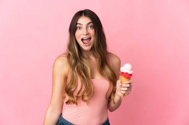 Kornet dondurması olan beyaz bir kadın. Pembe arka planda yalıtılmış. Yüz ifadesi şaşırtıcıydı.