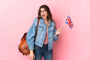 Young woman holding an United Kingdom flag isolated on pink background with surprise facial expression