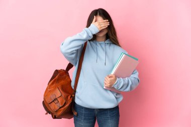 Pembe arka planda izole edilmiş genç bir kız öğrenci gözlerini elleriyle kapatıyor. Bir şey görmek istemiyorum.