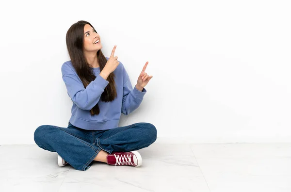若いです女性座って床に指差指で指差す素晴らしいアイデア — ストック写真
