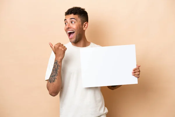 Young Brazilian Man Isolated Beige Background Holding Empty Placard Pointing — Stock fotografie