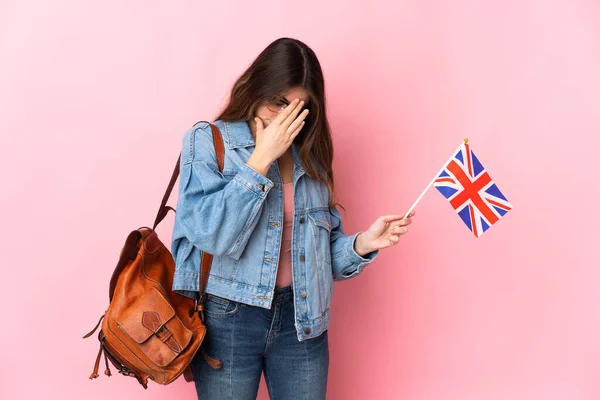 Young woman holding an United Kingdom flag isolated on pink background with tired and sick expression