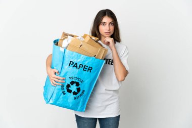 Young woman holding a recycling bag full of paper to recycle isolated on white background thinking