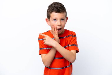 Little boy isolated on white background pointing to the side to present a product and whispering something