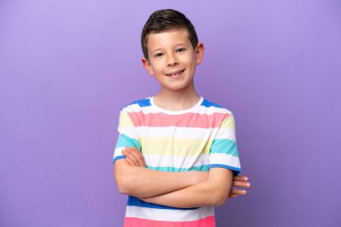 Little boy isolated on purple background keeping the arms crossed in frontal position