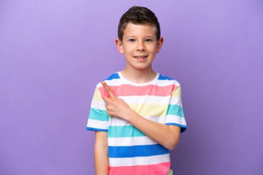 Mor arka planda izole edilmiş küçük çocuk bir ürünü sunmak için yan tarafı işaret ediyor.