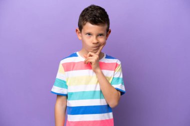 Little boy isolated on purple background and thinking