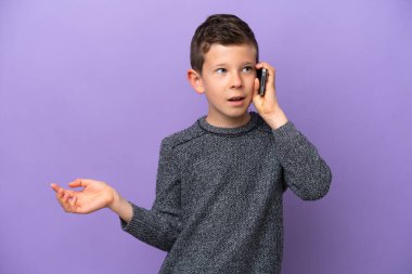 Mor arka planda izole edilmiş küçük bir çocuk cep telefonuyla biriyle sohbet ediyor.