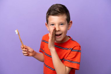 Little boy brushing teeth isolated on purple background whispering something