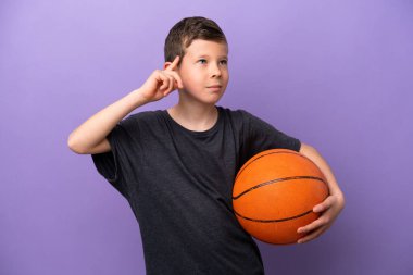 Mor arka planda izole edilmiş basketbol oynayan küçük çocuğun şüpheleri ve düşünceleri var.