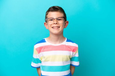 Mavi arka planda izole edilmiş küçük bir çocuk. Neşeli gözlüklü.