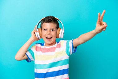 Küçük çocuk mavi arka planda izole edilmiş müzik dinliyor ve şarkı söylüyor.