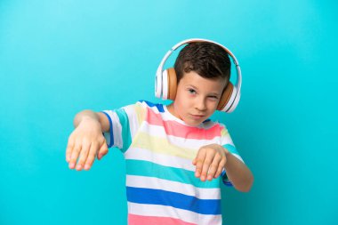 Küçük çocuk mavi arka planda izole edilmiş müzik ve dans dinliyor.