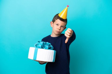 Küçük çocuk mavi arka planda izole edilmiş doğum günü pastası tutuyor.