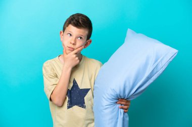 Mavi arka planda izole edilmiş pijamalı küçük bir çocuk şüpheleri var.