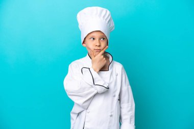 Küçük aşçı çocuk mavi arka planda mahsur kalmış, kuşkuları var.