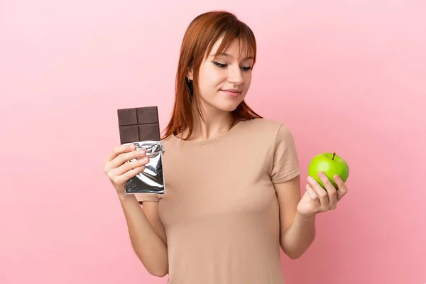 Zrzka Dívka Izolované Růžovém Pozadí Čokoládovou Tabletu Jedné Ruce Jablko — Stock fotografie