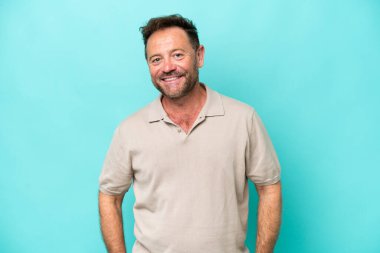 Orta yaşlı beyaz bir adam mavi arka planda izole edilmiş gülüyor.