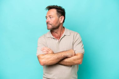 Orta yaşlı, beyaz bir adam mavi arka planda izole edilmiş.
