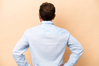 Middle age caucasian man isolated on beige background in back position