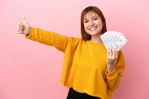 Redhead Girl Taking Lot Money Isolated Pink Background Giving Thumbs — Stock fotografie