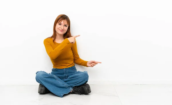 Roodharig Meisje Zit Vloer Geïsoleerd Witte Achtergrond Wijzend Vinger Naar — Stockfoto