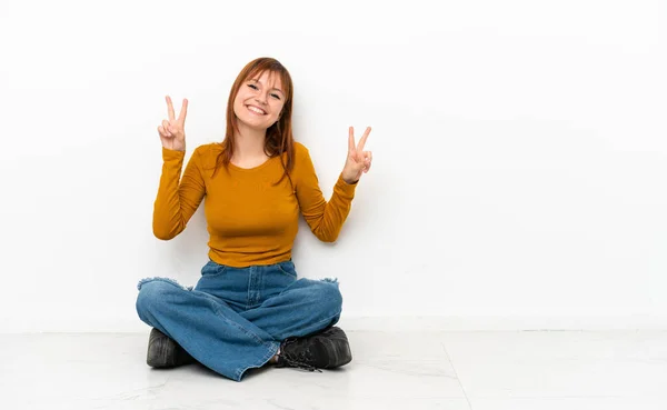Redhead Girl Sitting Floor Isolated White Background Showing Victory Sign — Stockfoto