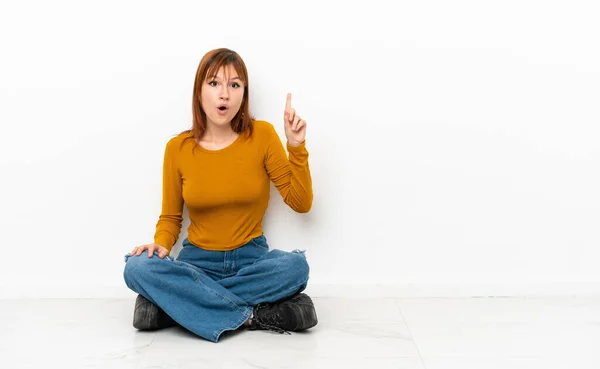 Redhead Girl Sitting Floor Isolated White Background Thinking Idea Pointing — ストック写真